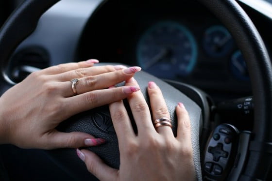 Female hands with manicure on a steering wheel of the automobile
